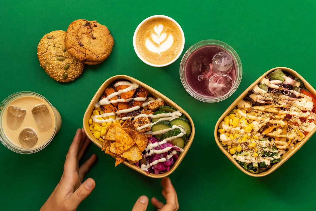 Een bowl, een salade, koffie en limonade van bovenaf op groen